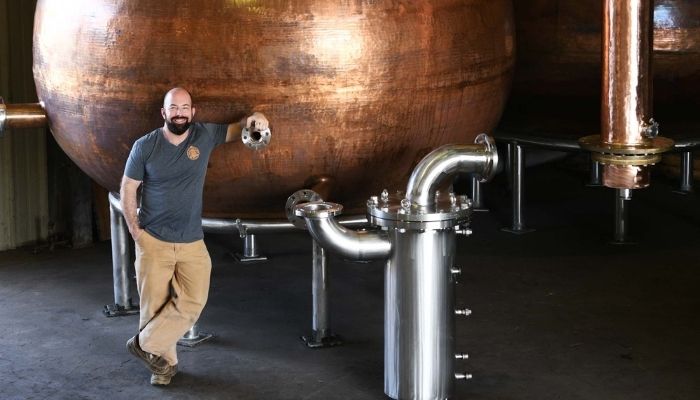 Chip Tate standing in front of his self-crafted copper pot still